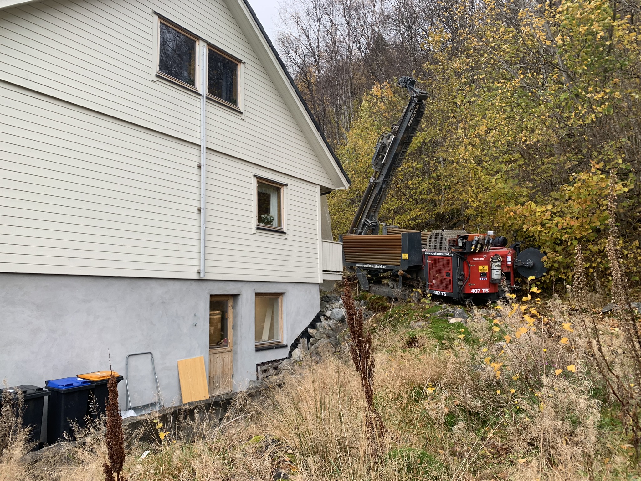 Borerriggen på plass, klar til å bore ned i berget ved siden av huset