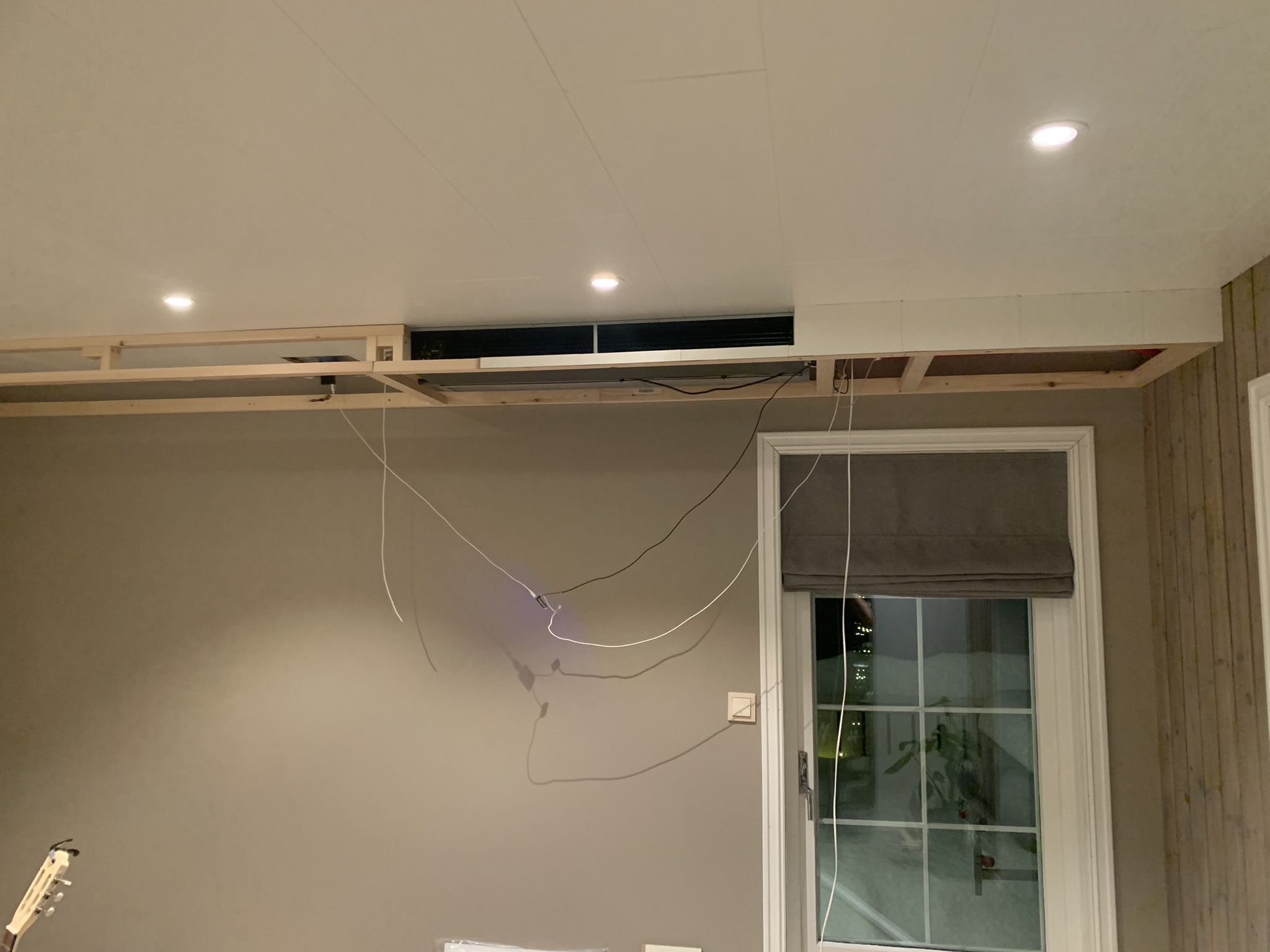 Trerammeverk bygget rundt enheten, himlingsplater delvis på plass. Ledninger henger fortsatt.