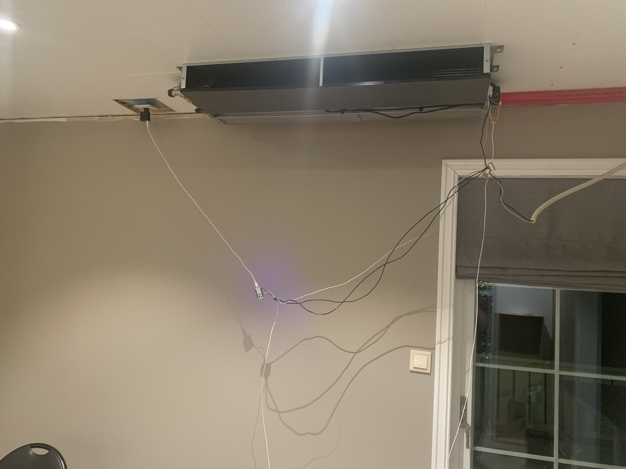 Viftekonvektoren montert øverst på veggen, med ledninger hengende ned. Himlingen ikke lukket ennå.